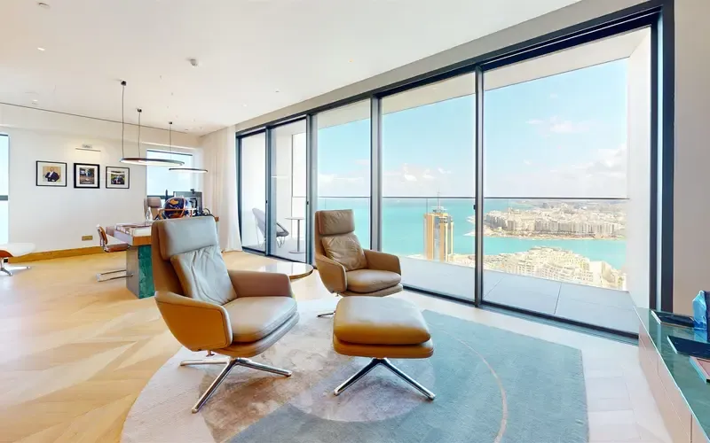 Penthouse living room with two leather armchairs, floor-to-ceiling windows and sea views